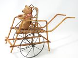 a teddy bear sitting in a wicker baby carriage