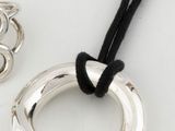 two pieces of silver jewelry sitting on top of a white surface