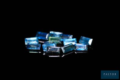 quelques cubes de verre bleus et verts posés sur une surface noire