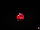 a close up of a red heart shaped diamond on a black surface