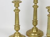 three brass candlesticks on a white surface with a white background