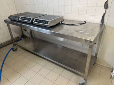 une table en acier inoxydable sur laquelle sont posés deux fours, dans une cuisine