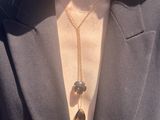 the woman is wearing a black jacket and a gold necklace