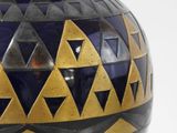 a blue and gold vase sitting on a white surface
