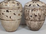 two vases sitting side by side on a white surface