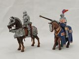 two figurines of knights riding on horses on a white surface