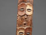 a wooden mask with three faces on it
