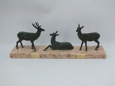 trois statues de cerfs en bronze posées sur un socle en marbre, sur fond blanc