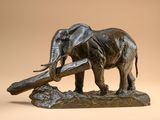 statue of an elephant holding a log in its trunk on a beige background