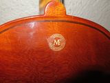 a close up of a wooden guitar case with a monogram on it