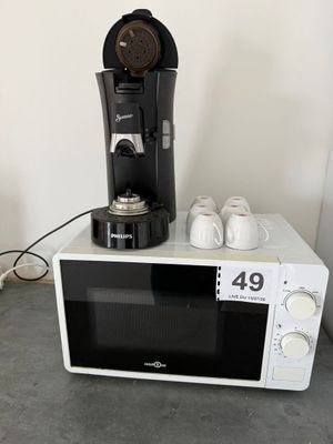 un micro-ondes blanc sur lequel est posée une cafetière