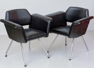 pair of black leather chairs with chrome legs on a white floor
