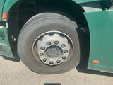 a large green truck with a flat tire on the road