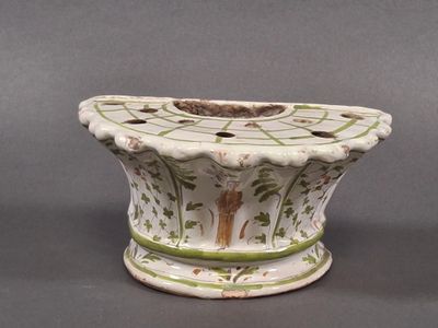 a white vase with green and brown designs on it