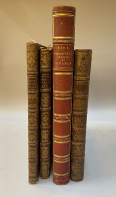 trois vieux livres empilés sur une surface blanche