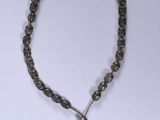 a close up of a necklace with a tassel on a white surface