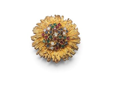 a close up of a gold brooch with colorful stones on a white surface