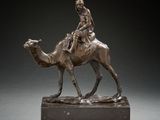 bronze statue of a man riding a camel on a marble base