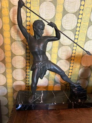 a statue of a man holding a spear on top of a table