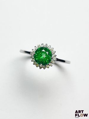 un gros plan d'une bague sertie d'un diamant vert sur une surface blanche