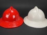 two red and white fire hats sitting next to each other on a black surface