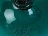 a green glass bowl with a black lid on a table