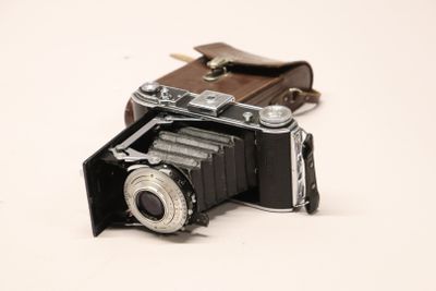 an old camera with a leather case on the table