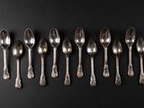 six silver spoons lined up in a row on a black surface