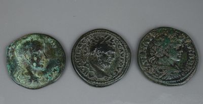 trois pièces de monnaie romaines anciennes, dont l'une présente un revers et l'autre un avers