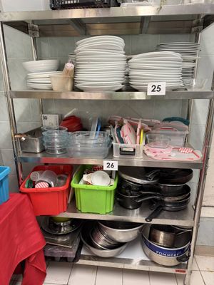 many dishes and pans on a metal shelf in a kitchen