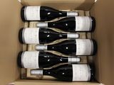 six bottles of wine in a cardboard box on a table