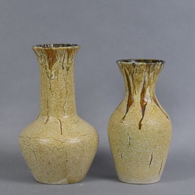 pair of yellow vases sitting on a gray surface with a gray background