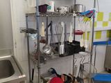 a metal shelf with pots and pans on it in a kitchen
