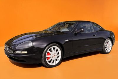 La voiture de sport noire est garée devant un mur orange.
