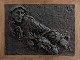 a black relief of a man sitting on a bench