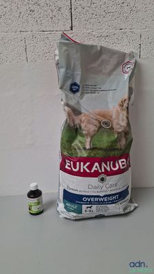 un sac de croquettes pour chien à côté d'un flacon d'huiles essentielles
