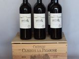 three bottles of red wine in a wooden crate on a table
