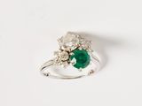 une image d'une bague avec une pierre verte entourée de diamants blancs