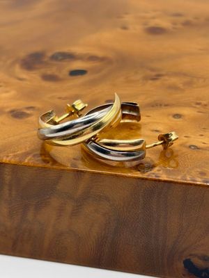 pair of gold and silver hoop earrings on a wooden surface