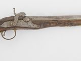 un vieux fusil exposé sur une surface blanche