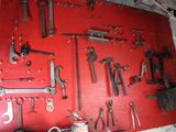 many tools hanging on a red wall in a garage