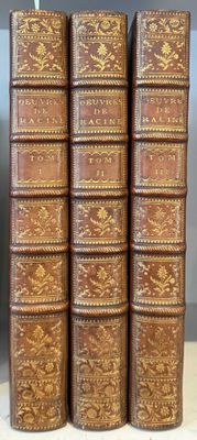 Quatre vieux livres sont alignés sur une étagère dans une pièce