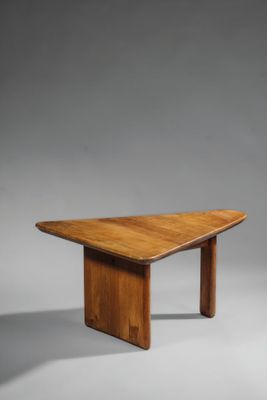 une table en bois dont le plateau est de forme triangulaire, sur fond gris