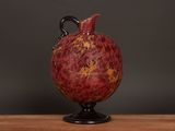 a red vase sitting on top of a wooden table