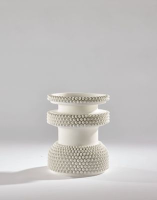 trois vases blancs empilés les uns sur les autres sur une surface blanche