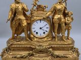 a gold clock with three figures on top of it