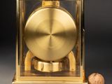 an image of a golden clock sitting on top of a table next to a cork