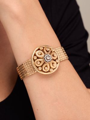 a close up of a woman wearing a gold bracelet with a diamond