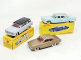 trois petites voitures sont posées sur des boîtes sur une surface blanche