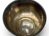 a metal bowl that is sitting on a white surface